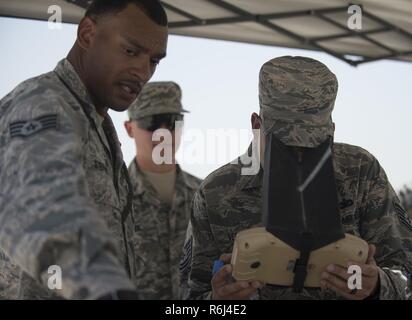 Ein US Air Force Airman sieht durch eine Flight Control Modul als Staff Sgt. Malcolm Stephen, Links, Assistant non-Offizier von Raven B Operationen mit 379 Expeditionary Sicherheitskräfte Squadron beauftragt, Gespräche über das, was die RQ-11 B Raven zeigt auf seine Farbe elektro-optischen Kamera im Al Udeid Air Base, Katar, 15. Mai 2017. Flieger von der 379 ESFS organisierte eine Woche der Strafverfolgung zu zivilen Polizisten Gefallenen Ehre, Sicherheitskräfte Flieger und US Air Force Office der speziellen Untersuchungen Agenten, die in der Linie der Aufgabe enthalten. Stockfoto