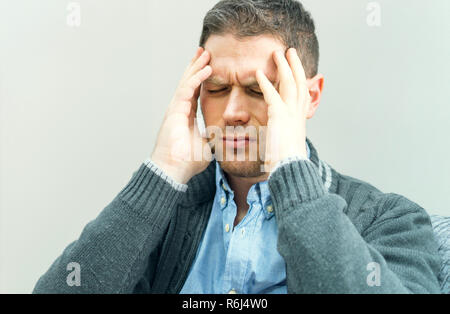 Stattliche unrasierte Mann mit Kopfschmerzen zu Hause. Stockfoto