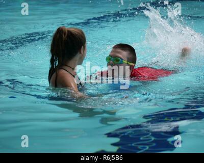 Braydon Gresham, Bereich 11 Athlet, konkurriert auf dem kickboard Schwimmen mit Hilfe von Sarah Lambert Hollingsworth, Assistant Coach, während der Special Olympics Mississippi 2017 Sommer Spiele an der Biloxi Natatorium Mai 20, 2017, auf Keesler Air Force Base, Fräulein Keesler bewirtete mehr als 3.200 Athleten, Direktoren, Trainer, Familie Mitglieder und freiwillige Helfer in über 16 Regionen in Mississippi für das 31. Jahr. Stockfoto