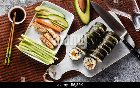 Banner von vegan Ready-made Sushi auf dem Tisch in Fisch. Brötchen mit gebratenem Tofu, Gurken, gekochte Karotten und frischen Avocado. Gesunde vegane Ernährung Stockfoto