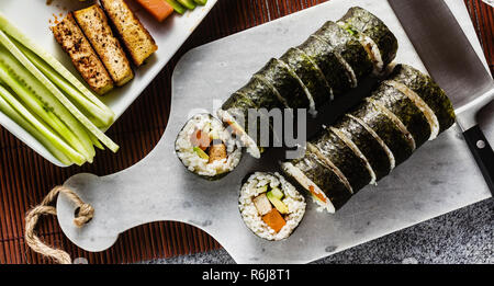 Banner von vegan Ready-made Sushi auf dem Tisch in Fisch. Brötchen mit gebratenem Tofu, Gurken, gekochte Karotten und frischen Avocado. Gesunde vegane Ernährung Stockfoto