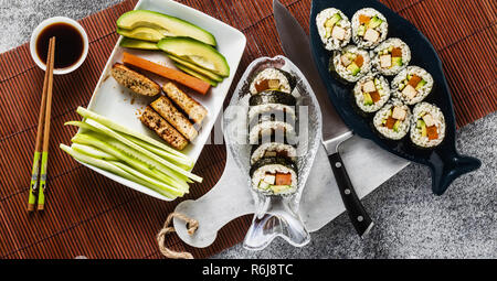 Banner von vegan Ready-made Sushi auf dem Tisch in Fisch. Brötchen mit gebratenem Tofu, Gurken, gekochte Karotten und frischen Avocado. Gesunde vegane Ernährung Stockfoto
