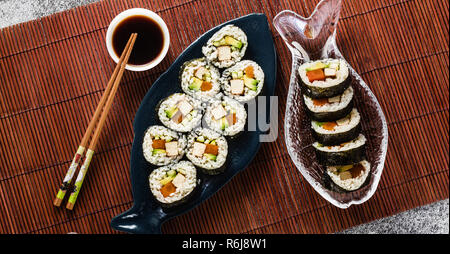 Banner von vegan Ready-made Sushi auf dem Tisch in Fisch. Brötchen mit gebratenem Tofu, Gurken, gekochte Karotten und frischen Avocado. Gesunde vegane Ernährung Stockfoto