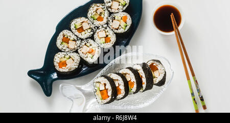 Vegan Ready-made Sushi auf dem Tisch in Fisch. Brötchen mit gebratenem Tofu, Gurken, gekochte Karotten und frischen Avocado. Gesunde vegane Ernährung Stockfoto