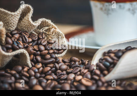 Geröstete Kaffeebohnen Verschüttete aus Sackleinen Sack auf Holz- Hintergrund Stockfoto