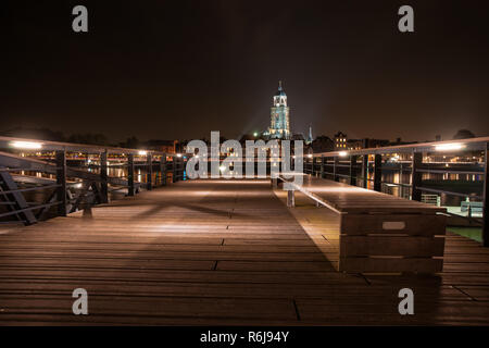 Bei Nacht mit Blick von einem Steg Deventer über die Ijssel. Der Turm der Kirche ist vor der Lebuinus wunderschön beleuchtet Stadtbild überragt. Stockfoto