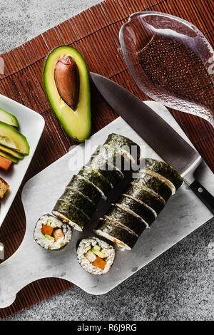 Vegan Ready-made Sushi auf dem Tisch in Fisch. Brötchen mit gebratenem Tofu, Gurken, gekochte Karotten und frischen Avocado. Gesunde vegane Ernährung Stockfoto