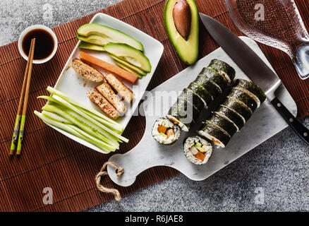Vegan Ready-made Sushi auf dem Tisch in Fisch. Brötchen mit gebratenem Tofu, Gurken, gekochte Karotten und frischen Avocado. Gesunde vegane Ernährung Stockfoto