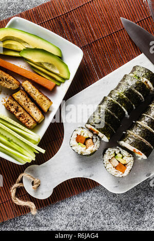 Vegan Ready-made Sushi auf dem Tisch in Fisch. Brötchen mit gebratenem Tofu, Gurken, gekochte Karotten und frischen Avocado. Gesunde vegane Ernährung Stockfoto