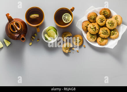 Hausgemachte Kekse, Mandeln und Sesam Kekse mit Pistazien. Gesunde vegane Glutenfreie Backwaren auf den Tisch mit einem Wasserkocher mit grünem Tee und Cups. t Stockfoto