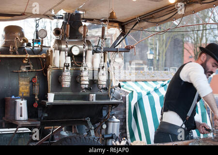 Vintage barista vorbereiten, um Kaffee zu Kunden im alten Stil Maschine mit handgefertigten Retro-look und throwback Kleidung in einen Marktstand Stockfoto