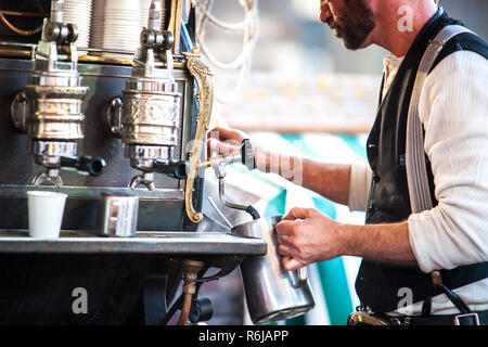 Vintage barista vorbereiten, um Kaffee zu Kunden im alten Stil Maschine mit handgefertigten Retro-look und throwback Kleidung in einen Marktstand Stockfoto