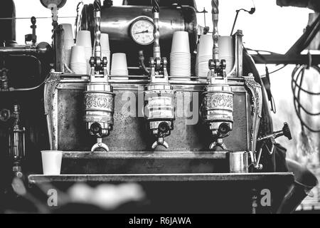 Vintage barista vorbereiten, um Kaffee zu Kunden im alten Stil Maschine mit handgefertigten Retro-look und throwback Kleidung in einen Marktstand Stockfoto