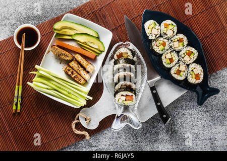 Vegan Ready-made Sushi auf dem Tisch in Fisch. Brötchen mit gebratenem Tofu, Gurken, gekochte Karotten und frischen Avocado. Gesunde vegane Ernährung Stockfoto