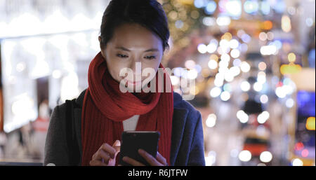 Frau, die Nutzung von Mobiltelefonen in der Stadt über den Hintergrund Stockfoto