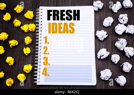 Konzeptionelle Hand schreiben Bildunterschrift mit frischen Ideen. Business Konzept für Denken Inspiration Inspiration Kreativität auf notepad Hinweis notebook Buch Holz- Hintergrund mit klebrigen gefaltete Gelb und Weiß Stockfoto