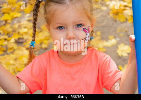 Mädchen schwingen auf Swing und Suchen in der Kamera Stockfoto