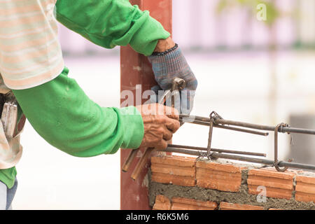 Arbeitnehmer mit Stahl Draht und Zange bewehrungsstahl vor Beton gegossen Stockfoto