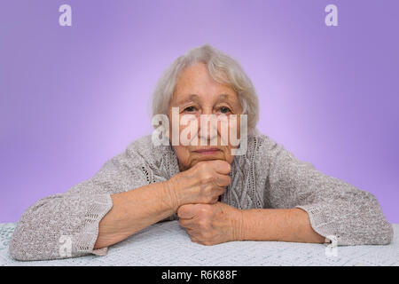Senior grau behaarte Frau träumen auf blauem Hintergrund isoliert Stockfoto