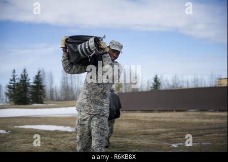 Us Air Force Airman 1st Class Jerred Davis, ein 354 Bauingenieur Squadron Pflaster- und Baumaschinen operator, trägt ein Schlauch April 10, 2017, at Eielson Air Force Base, Alaska. Während der Pause-Saison, Flieger im Schnee Scheune verwenden, um die Schläuche zu Wasser von der Flight Line, um sicherzustellen, dass die Flying Mission nicht betroffen ist. Stockfoto