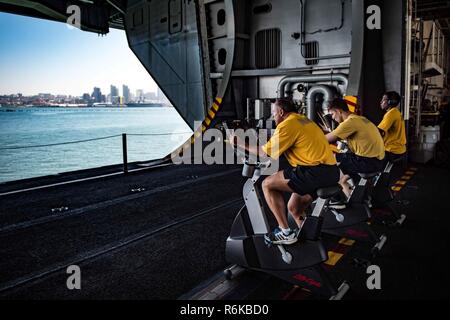 SAN DIEGO (22. Mai 2017) Segler ihre bi-jährlichen körperlichen Readiness Test (PRT) auf stationären Fahrrädern im Hangar Bucht der Flugzeugträger USS Theodore Roosevelt (CVN 71). Das Schiff ist günstig pier Seite in ihren Heimathafen San Diego nach Abschluss der maßgeschneiderten Ausbildung an Land, die Verfügbarkeit und die abschließende Bewertung Problem. Stockfoto