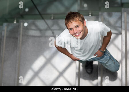 Hübscher junger Mann, der in einem Treppenhaus, suchen, schauen, glücklich und motiviert (Farbe getonte Bild) Stockfoto