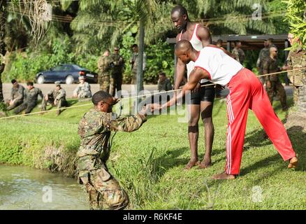 Ghana Armed Forces Instructor zieht der US-Army Staff Sgt. Reginald Gracia auf die 1 Battalion, 506Th Infantry Regiment, 1st Brigade Combat Team, Luftlandedivision, aus dem Wasser während der Vereinigten Accord 2017 Jungle Warfare Schule zugewiesen auf Achiase Militärbasis in Akim Oda, Ghana am 22. Mai 2017. Die Jungle Warfare School ist eine Reihe von situativen Übungen entwickelt, die Teilnehmer in die Train-Aufstand und die innere Sicherheit. Stockfoto