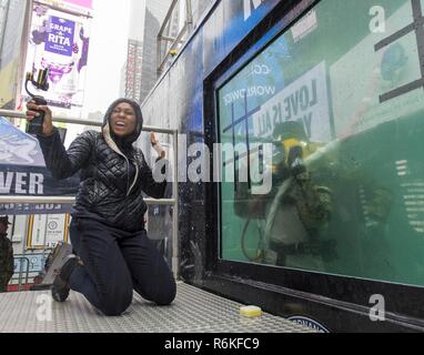 NEW YORK (25. Mai 2017) Rachel Scott, ein Reporter mit ABC News Digital, gewinnt ein Spiel von Tic-tac-toe gegen Marine Diver 1. Klasse Dave Kanone, die Mobile Tauchen und Bergung (MDSU) 2, während eine live Übertragung bei der Beseitigung von Explosivstoffen Gruppe (EODGRU) 2 Static Display und tauchen Tank im Times Square im Rahmen der Fleet Week New York 2017 zugeordnet. Fleet Week New York, der nun in seinem 29. Jahr, ist die Stadt der Zeit - Feier des Meeres Leistungen geehrt. Es ist eine einmalige Chance für die Bürger von New York und die umliegenden Tri-state-Area zu treffen Seemänner, Marinesoldaten und Küstenwache, eine Stockfoto