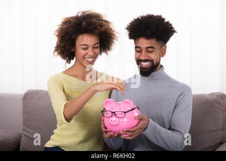 Paar einfügen Münze in Sparschwein Stockfoto