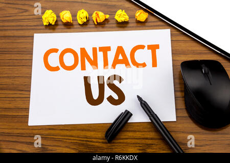 Konzeptionelle Hand schreiben Text anzeigen Kontakt mit uns auf. Business Konzept für Kundenservice auf haftnotiz Papier geschrieben auf dem hölzernen Hintergrund mit Marker mit der Maus und Tablet office anzeigen. Stockfoto