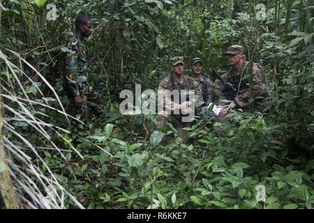 Ghana Streitkräfte Sgt. Francis Kofi Donkor beobachtet, als US-Soldaten auf die 1 Battalion, 506Th Infantry Regiment, 1st Brigade Combat Team, Luftlandedivision durch den Dschungel während United Accord 2017 Jungle Warfare School navigieren auf Achiase Militärbasis, Akim Oda, Ghana, 26. Mai 2017. Die Jungle Warfare School ist eine Reihe von situativen Übungen entwickelt, die Teilnehmer in die Train-Aufstand und die innere Sicherheit. Stockfoto