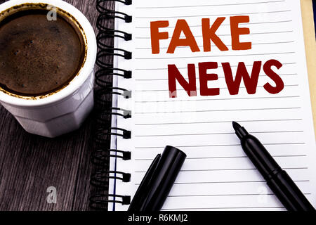 Schreiben Text anzeigen gefälschte Nachrichten. Business Konzept für Hoax Journalismus auf Notebook buch Hinweis Papier auf dem Holz Holz Hintergrund geschrieben. Mit Kaffee und schwarzen Marker. Stockfoto