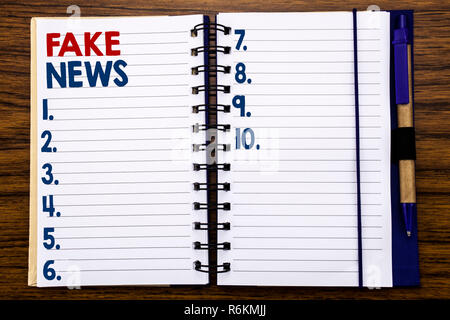 Schreiben Text anzeigen gefälschte Nachrichten. Business Konzept für Hoax Journalismus auf Notebook Hinweis Papier, Holz- Hintergrund mit Stifte und Marker. Stockfoto