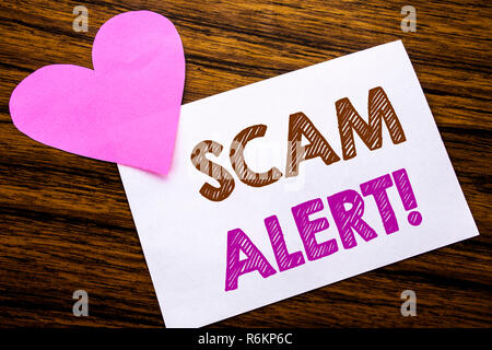 Konzeptionelle Hand schreiben Text übersicht scam Alert. Konzept für Betrug Warnung auf haftnotiz Papier, Holz Holz Hintergrund. Mit rosa Herz bedeutet Liebe Anbetung. Stockfoto