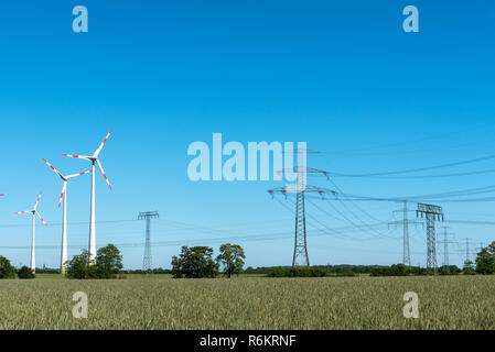 Stromleitungen in Windkraftanlagen an einem sonnigen Tag in Deutschland Stockfoto