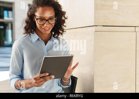 Junge Frau mit Brille Lesen und Surfen auf digital Tablet Stockfoto