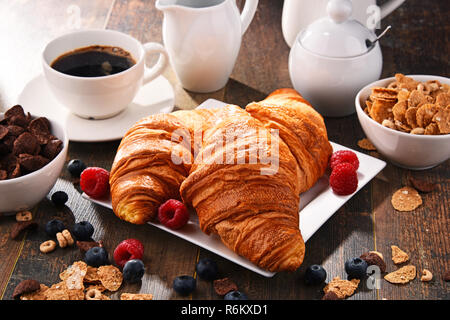 Frühstück serviert mit Kaffee, Croissants, Müsli und Obst Stockfoto