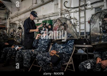 Pazifik (22. Mai 2017) Segler erhalten Gasmaske passen Tests im Hangar Bucht der Flugzeugträger USS Theodore Roosevelt (CVN 71). Theodore Roosevelt ist derzeit pier Seite in ihren Heimathafen San Diego günstig nach der vor kurzem die Vollendung der maßgeschneiderten Ausbildung an Land, die Verfügbarkeit und die abschließende Bewertung Problem (TSTA/FEP). Stockfoto