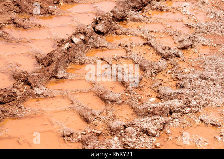 Das Rad auf der Straße, Pfützen und Schlamm nach Regen. Spuren am Boden von Traktor, Bagger, Auto, Automobil Reifenspuren auf matschigen Weg. Sandigen weg. Stockfoto