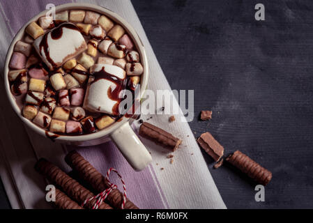 Milch Schokolade Tasse mit Marshmallows und choco Richtfest an der Spitze. Weihnachten süße Speisen mit heißer Schokolade, Marshmallows und Schokolade klebt auf einem Handtuch Stockfoto
