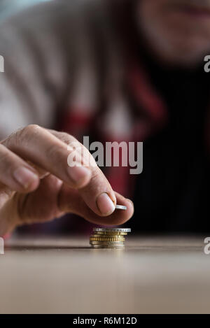 Nahaufnahme der älteren wohnungslosen Menschen zählen von Münzen auf hölzernen Schreibtisch stapelt sie. Stockfoto