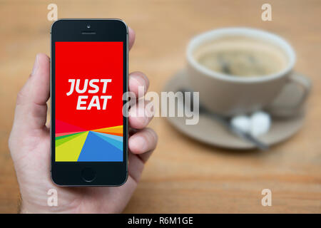 Ein Mann schaut auf seinem iPhone die zeigt die einfach Essen Logo (nur redaktionelle Nutzung). Stockfoto