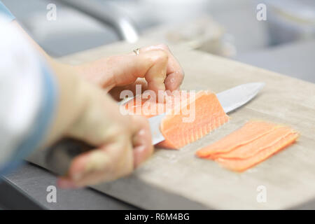 Bis zu schließen. Küchenchef schneiden Fisch für Sushi Stockfoto