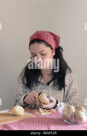 Brünette Frau Schälen von Kartoffeln Stockfoto