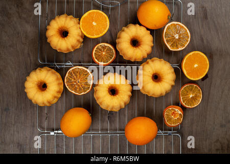 Kleine orange bundt Kuchen mit frischen und trockenen Orangen auf Kühlung ruck, Ansicht von oben, flach Stockfoto
