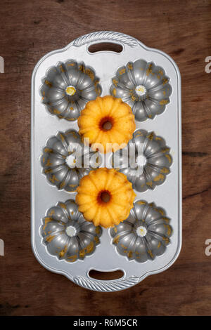 Zwei kleine orange Bundt Kuchen auf leer Metall kochen Schimmel, Ansicht von oben, flach Stockfoto