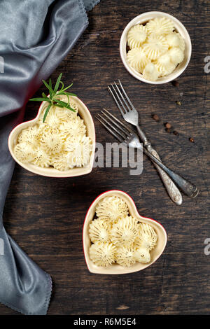 Shepherd's Pie in kleinen, individuellen Herzform rot ramikens, traditionelle britische Gerichte mit Hackfleisch und Kartoffelbrei auf rustikalen Holztisch, top v Stockfoto