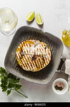 Schwertfisch Steak gebraten auf Grill Pfanne mit Olivenöl und Gewürzen. Weißwein Glas Stockfoto