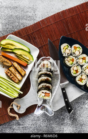 Vegan Ready-made Sushi auf dem Tisch in Fisch. Brötchen mit gebratenem Tofu, Gurken, gekochte Karotten und frischen Avocado. Gesunde vegane Ernährung Stockfoto