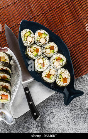 Vegan Ready-made Sushi auf dem Tisch in Fisch. Brötchen mit gebratenem Tofu, Gurken, gekochte Karotten und frischen Avocado. Gesunde vegane Ernährung Stockfoto